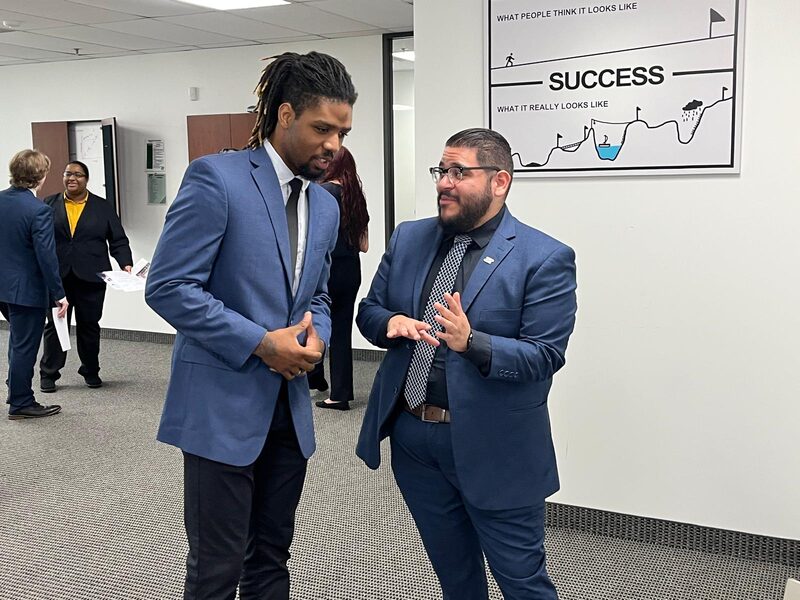 Two 5 Pillar Solutions team members in conversation by a success poster