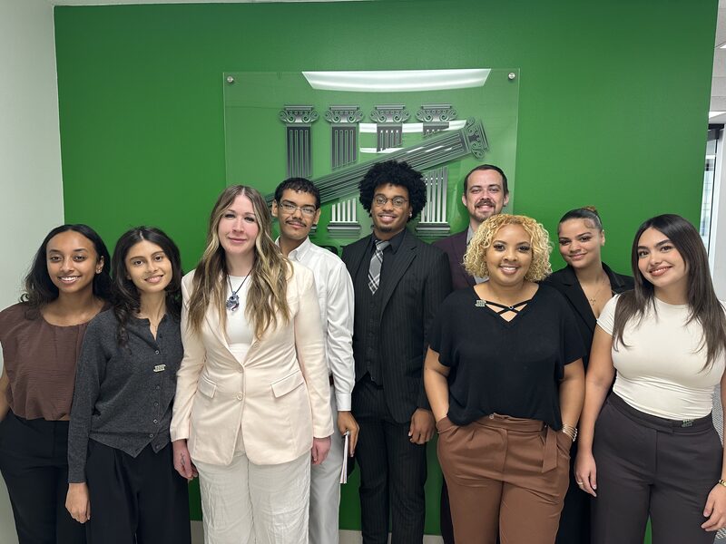 The 5 Pillar Solutions team in front of the company logo wall