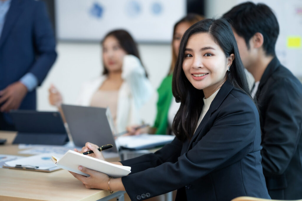 A young sales intern looking happy as she engages with a team discussion in the boardroom.